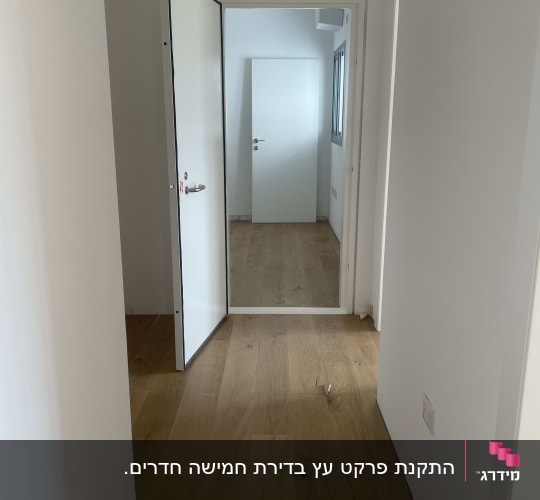 פרקט עץ בהיר במסדרון עם דלתות לבנות